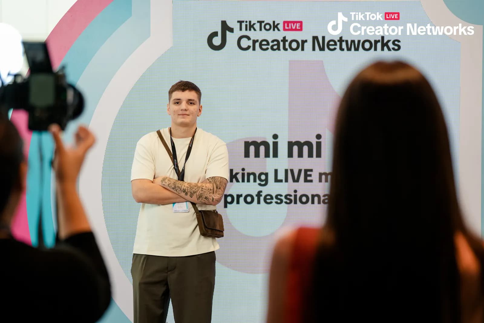 Представник mi mi біля стіни Creator Networks із написом «mi mi — making LIVE more professional», поруч фотограф